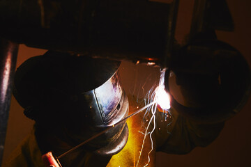 Man in protective mask welding metal construction.