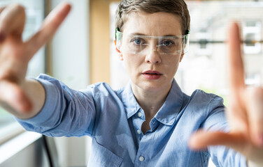 Woman in office wearing AR glasses focusing on future technology