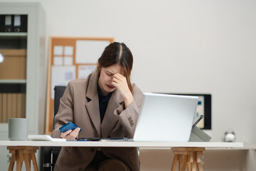 Sad businesswoman is sitting at table, covering his face with his hand and talking on cell phone.