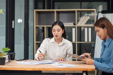  Group of happy Asian business people having a meeting at the office. Two women working together using modern laptops.