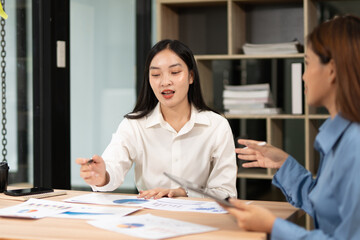 Group of happy Asian business people having a meeting at the office. Two women working together using modern laptops.