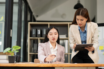 Group of happy Asian business people having a meeting at the office. Two women working together using modern laptops.