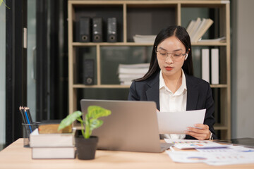 Happy businesswoman wearing glasses at work using modern laptop