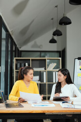 Group of happy Asian business people having a meeting at the office. Two women working together using modern laptops.
