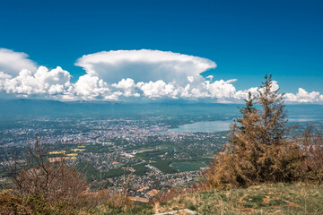 Vue panoramique spectaculaire du bassin genevois depuis le Salève, révélant la ville de Genève, le lac Léman et les montagnes environnantes sous une lumière naturelle et dégagée.