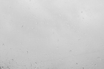 Rain drops on a window pane create a natural texture. Transparent liquid element for background or overlay effect concept on a gray surface.