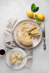 Homemade lemon pie with streusel on light table with cut piece and cup of coffee, top view, copy space