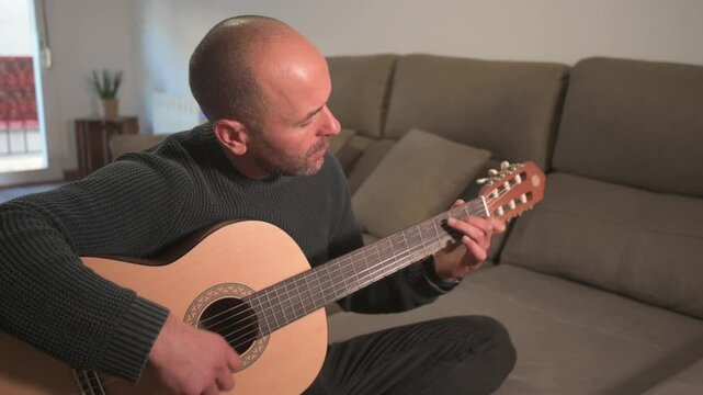 Musician playing acoustic guitar at home