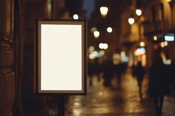 Blank vertical digital billboard stands empty in a bustling city street during nighttime with pedestrians and street lights illuminating the surroundings