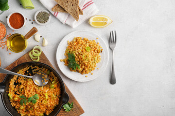 Red lentils dal in black pan and on plate on white table top. Lentils carrot and lettuce vegetarian meal, top view copy space