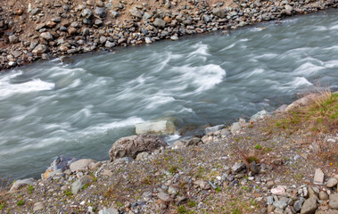 A river with a rocky shoreline and a few rocks in the water