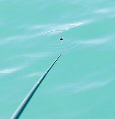 A fishing pole with a hook and a red and black lure on it