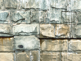 A wall made of stone with a few cracks and some water stains