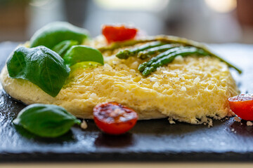 Omelet with baked asparagus, tomatoes and basil. Close-up, background. For use in menus and banners. The concept of a delicious and healthy breakfast.