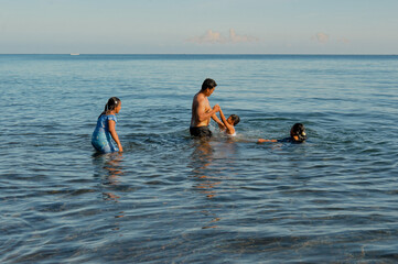 In a tender moment, the little boy asks to be held by his father while standing in the shallow...