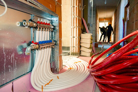 Heap of pipes go through concrete floor. Heat pump distributer for heating the residential building
