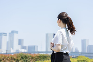 都会のビル群を見つめるビジネスウーマン