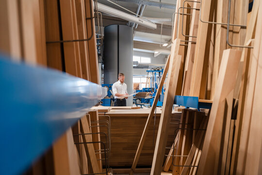 Carpenter standing in production hall with ring binder in hands