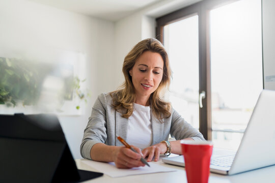 Businesswoman signing contract at desk in office