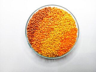 Gradation masterbatch granules in a circular glass container isolated on a white background,...