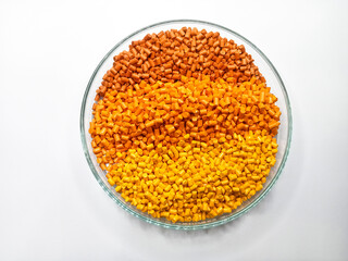 Gradation masterbatch granules in a circular glass container isolated on a white background, suitable as a product catalog photo design for a plastic manufacturing industry company profile