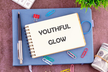A spiral notebook is open with the phrase youthful glow prominently displayed. The arrangement...