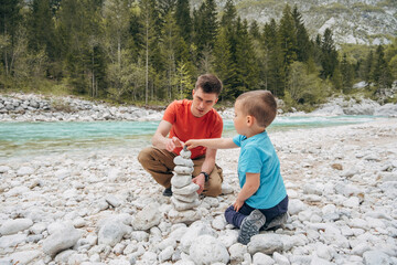 Father and son stacking pebbles on a riber bank