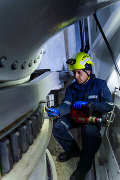 Engineer performing maintenance on a wind turbine nacelle gearbox indoors