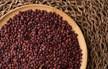 Organic uncooked seeds dark red brown lentils.