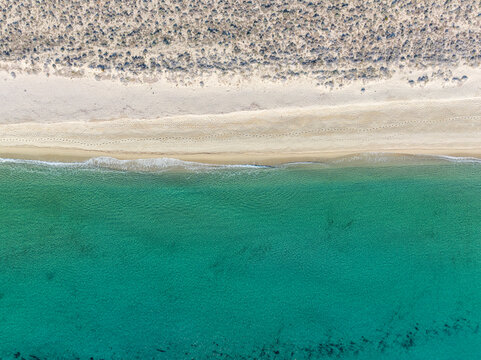 Aerial view of Spiaggia Di Sutt'e Riu beach in Posada, Sardinia, Italy with turquoise water and sandy shoreline.