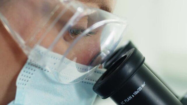 A scientist works with a microscope in the laboratory. Conducts research of biomaterial samples.