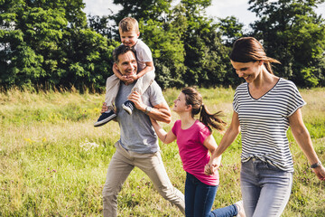 Happy family holding hands while running on grass