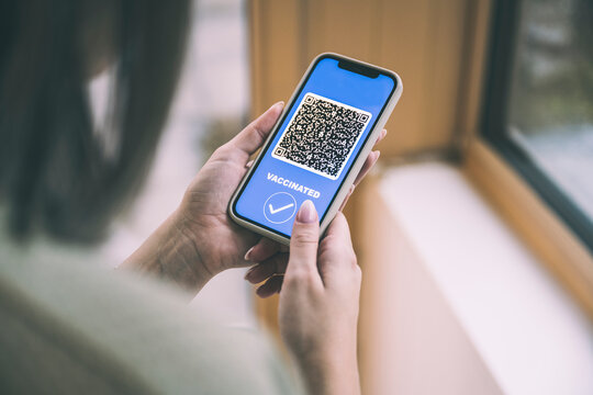 Woman with vaccination certificate QR code on mobile phone screen