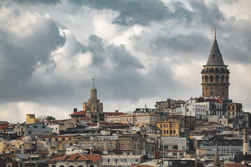 Naklejka premium Skyline of Istanbul featuring historic architecture and Galata Tower under dramatic cloudy sky
