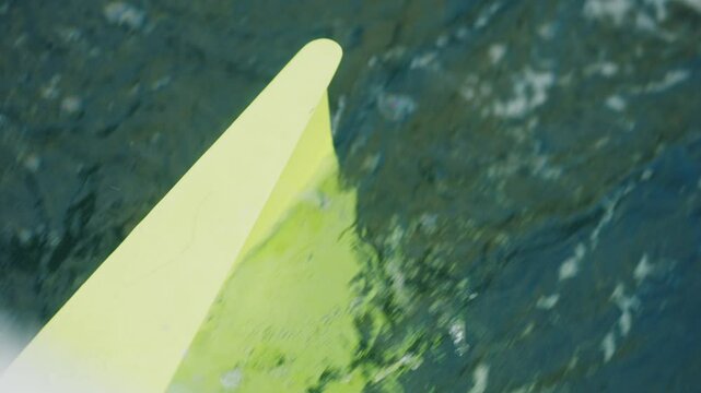 Close-up of a yellow daggerboard slicing through dark sea water, seen from a Class 40 racing sailboat