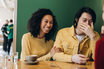 Smiling, happy friends laughing and enjoying coffee at cafe table