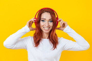 Young caucasian smiling happy friendly woman in white casual shirt t-shirt wearing red wireless headphones isolated on yellow background studio portrait.