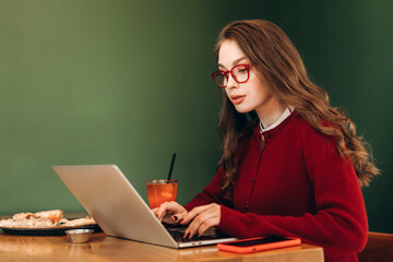 Freelancer working on laptop in cafe with pizza and juice