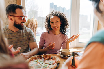 Friends enjoying pizza and conversation in a restaurant by the window