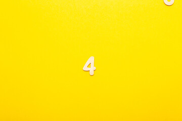 Top view of wooden number 4 four on yellow bright background.