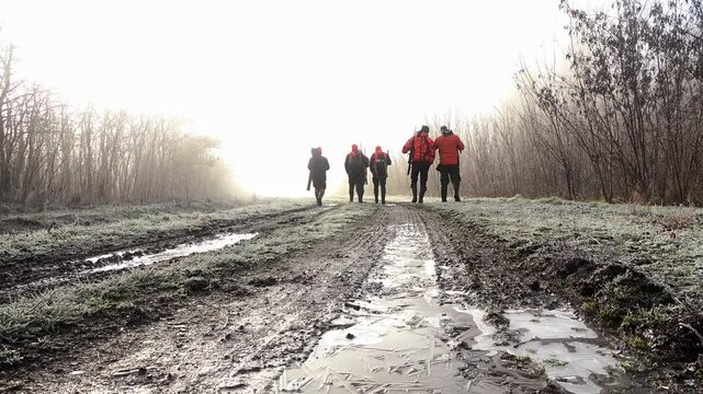 Group of hunters walking through misty forest trails in Nikinci Serbia during early morning light