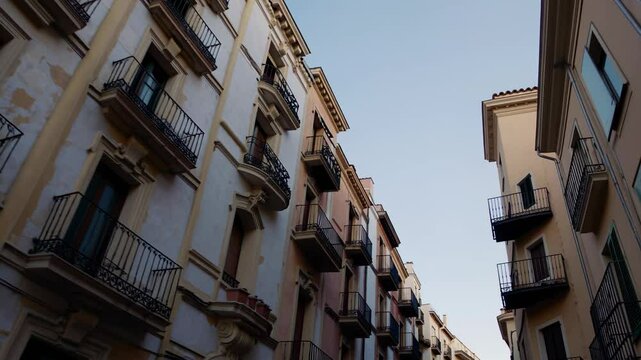 Row of old European apartment buildings with balconies and weathered facades under clear sky

