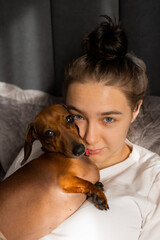 teenage girl cuddles at home with a dachshund dog
