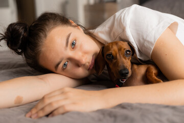 teenage girl cuddles at home with a dachshund dog