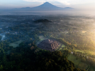 Misty Borobudur temple in the morning with the Merapi, Merbabu and Arjuno mountain in the...