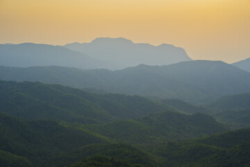 Breathtaking mountain landscape sunset, showcasing layered hills and warm golden sky. serene atmosphere evokes tranquility