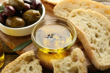 Slices of bread with oil, spices and olives on wooden table, closeup