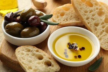 Slices of bread with oil, spices and olives on light table, closeup