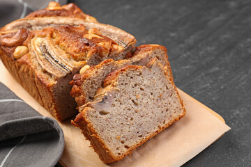 Cut banana bread with nuts on black table, closeup