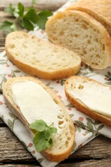 Pieces of bread with butter and parsley on wooden table, closeup